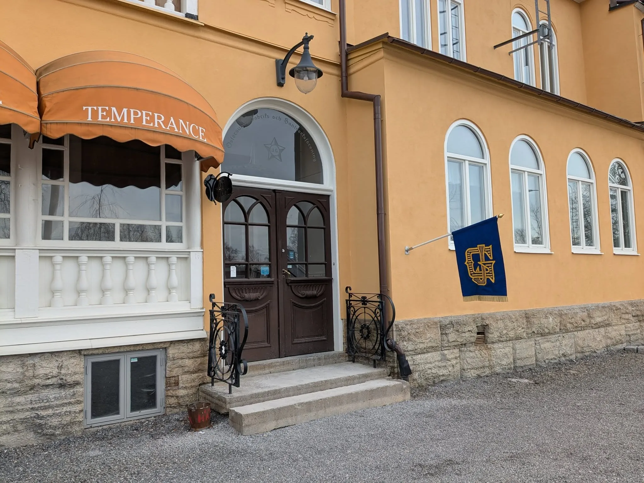 Entrén till Temperance med Gillesflaggan i blått och guld på den gula fasaden.