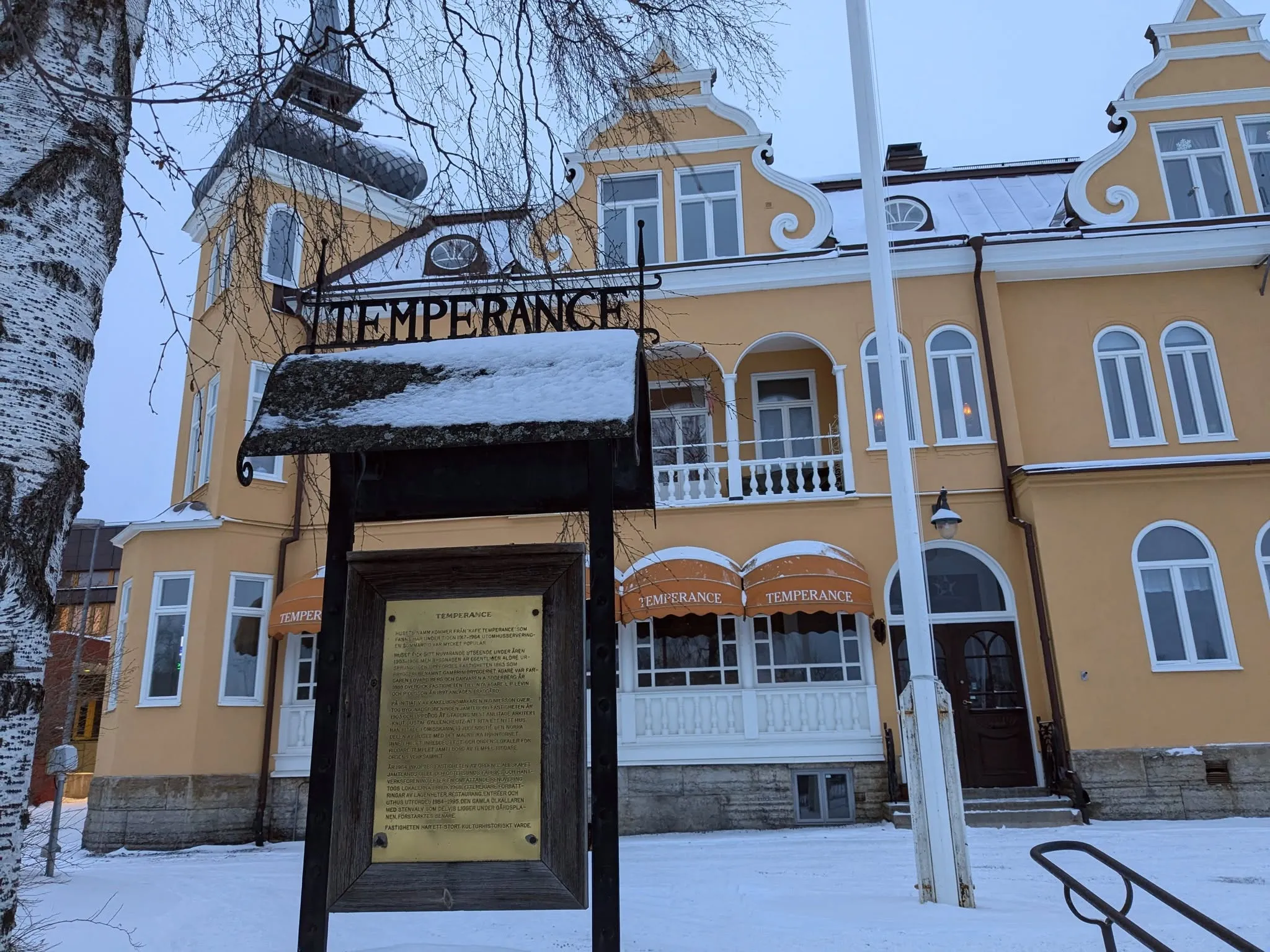 Järnskylt med texten Temperance framför huset en vinterdag, och en mässingsplakett med husets historia.